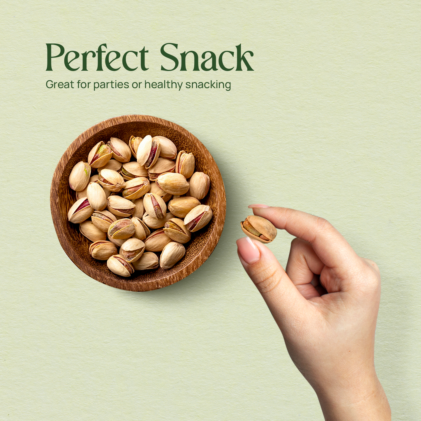 Salted pistachios in a wooden bowl with a hand reaching toward the nuts