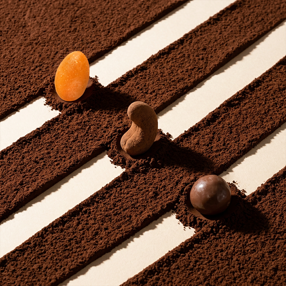 Chocolate dragees on cocoa and white stripes: orange, brown, and dark pieces