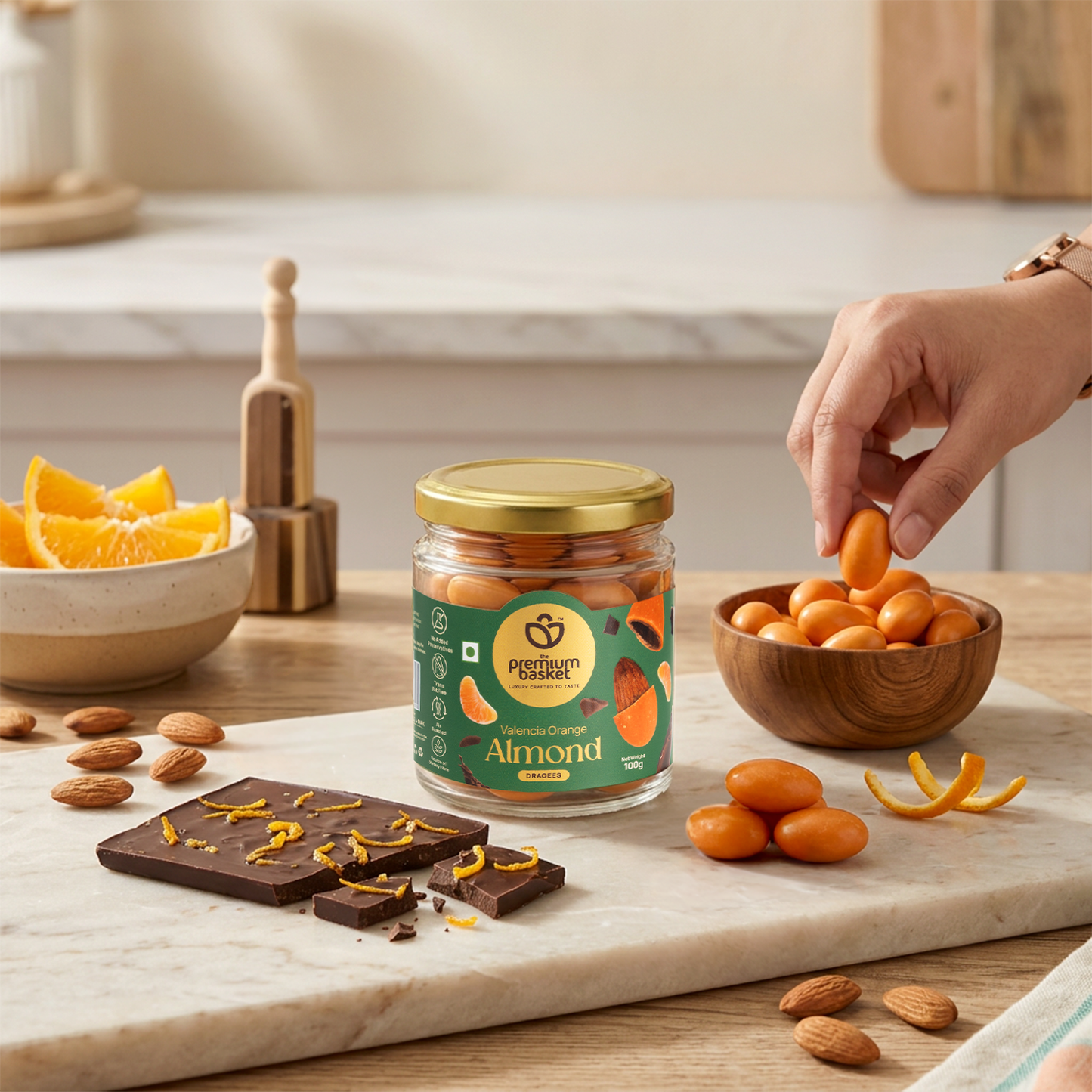 Valencia Orange Almond jar with gold lid, almonds in a wooden bowl, orange garnish