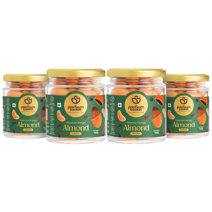 Four glass jars of orange-flavored almond snacks with gold lids and green labels